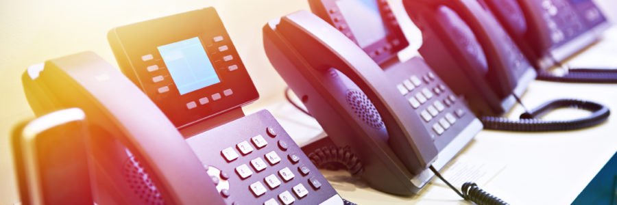 A row of modern office desk phones with digital displays-what is voip