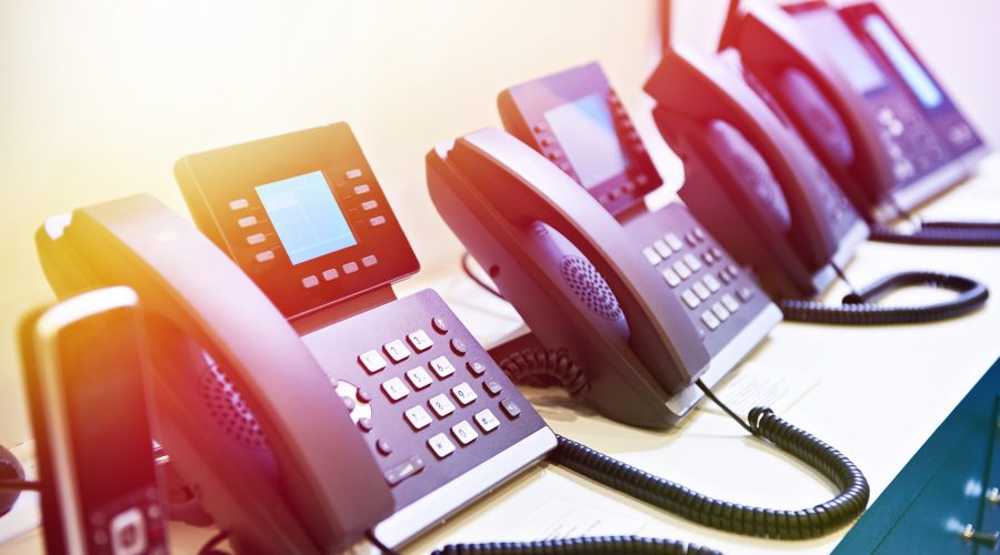 A row of modern office desk phones with digital displays-what is voip