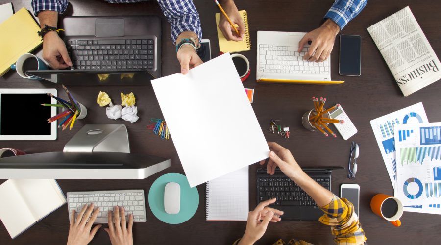 Top-down view of a collaborative workspace with multiple people working on laptops-office 365