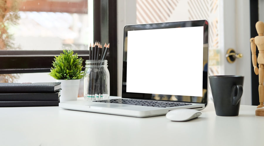 Minimalist workspace with a laptop, books, and a coffee cup on a white desk-device cleanup